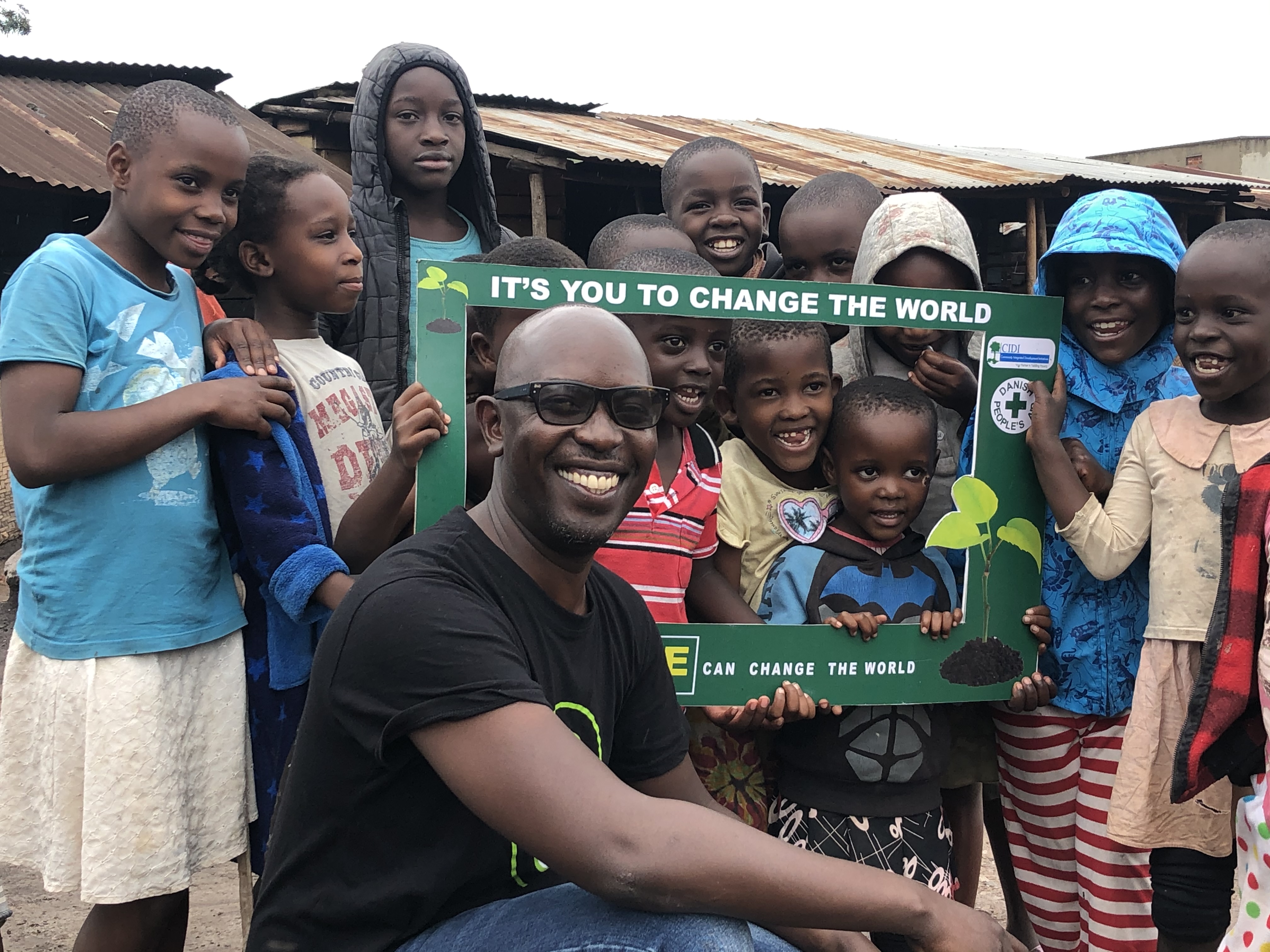 Community engagement with children holding change the world frame
